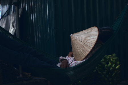 A dark shot of a sleeping female who covered her face with conical hat non la in Vietnam