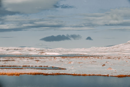 A beautiful view of a lake covered in snow under a cloudy sky