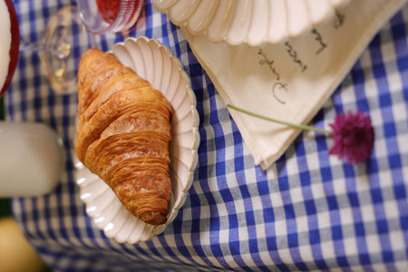 A closeup shot of a fresh croissant served on the white plate with a double color sweet dessertの写真素材