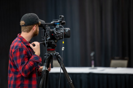 A side view of the operator with camera preparing to record the meeting in the conference hall