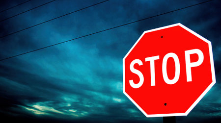 A scenic shot of the Stop Sign in the twilight dark with a cloudy skyの写真素材