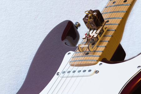 A miniature Santa Claus sleigh and gift package decor on an electric guitar on a white backgroundの写真素材