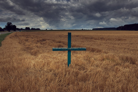 A view of the cross in the field on a cloudy dayの写真素材