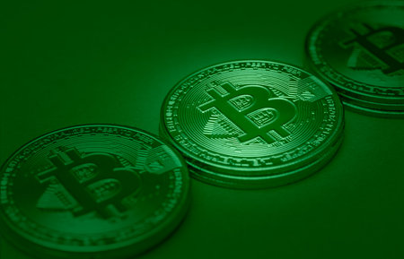 A closeup shot of golden Bitcoins isolated on a green background