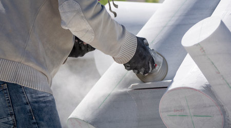 A selective focus shot of an industrial worker cutting stone with a grinder