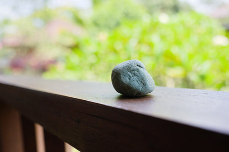 A closeup shot of a small stone on the fence of balcony with trees in the backgroundの写真素材