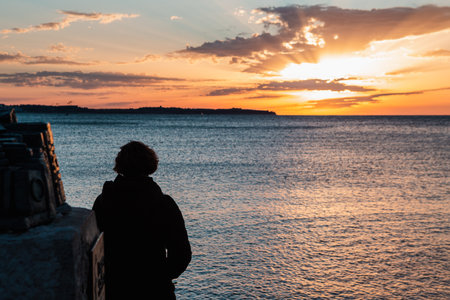 A silhouette of a person by the sea enjoying the beautiful view of the sunset
