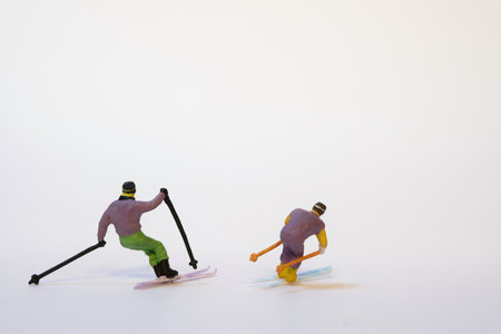 Two miniature skiers in action - white background, copy space