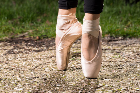 A closeup of a ballerina in pointe shoes on the rocky ground