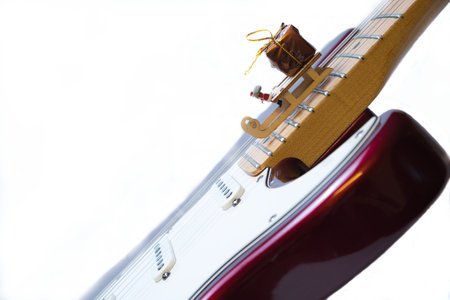 A miniature Santa Claus sleigh and gift package decor on an electric guitar on a white background