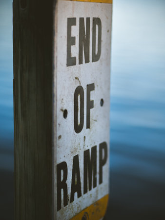 A vertical shot of end of ramp sign on a wooden log at a pier