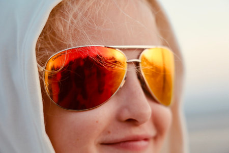 A portrait of a female kid with sunglasses and a hooded sweatshirt
