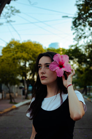 A vertical shot of a young beautiful female posing with a pink Hibiscus flower