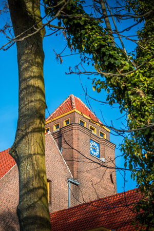 A vertical shot of a Church tower with trees in the foreground