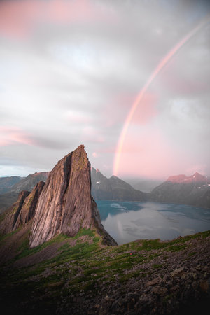A vertical shot of a Segla mountain peak and a rainbow in the backgroundの写真素材