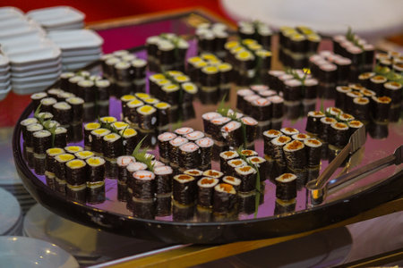 A closeup of different sushi rolls on a huge tray on the table in a restaurantの写真素材