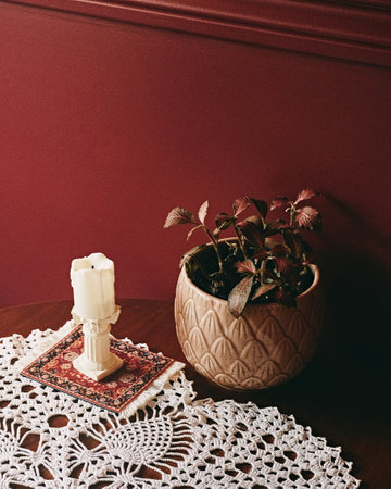 A vertical closeup shot of a wooden table with a dry potted plant and a candle