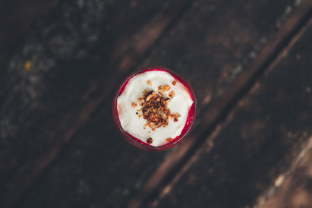 A top view of a pudding with whipped cream and strawberries on a wooden tableの写真素材