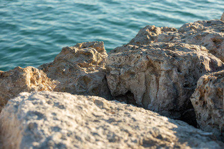 A closeup of rocks near water sea on a sunny day in Doha, Qatarの写真素材