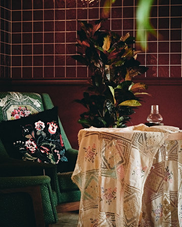 A vertical shot of a red cafe interior with a sofa and a pillow