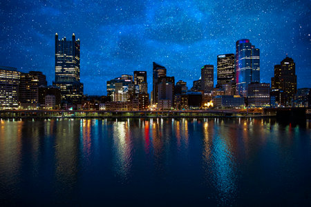 A mesmerizing cityscape view on the coast of the lake against a dark starry sky at night