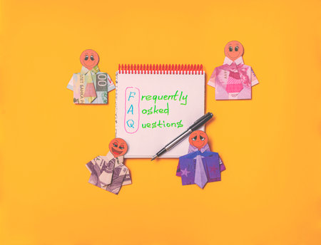 Notepad with inscription FAQ and fountain pen Around him lie mannequins of happy people in shirts...
