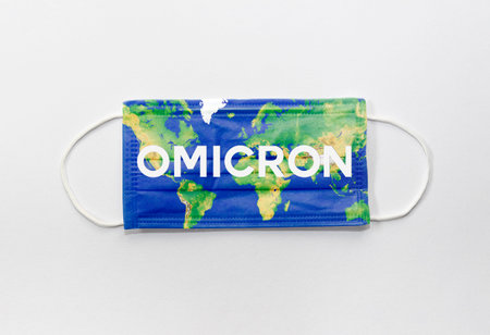 Health care and medical concept with protective covid face mask with globe and new B.1.1.529 omicron variant text on white background.の写真素材