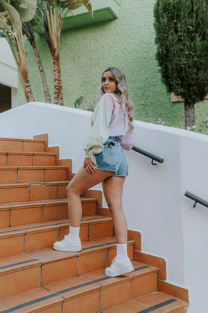 A Caucasian blonde pretty girl posing in the park under the sun with a summer outfitの写真素材