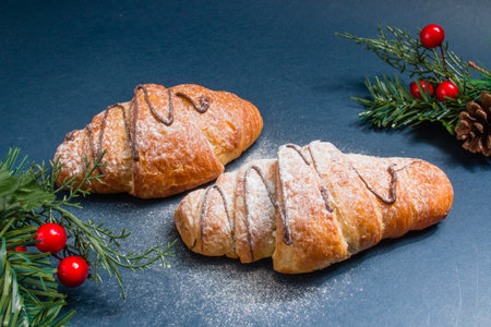 A selective focus shot of croissants with holiday ornaments on a black surfaceの写真素材