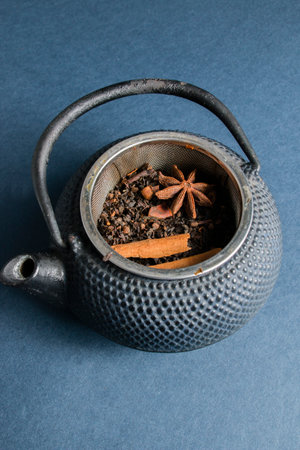 A top view of a teapot with its fresh dried ingredients for a tea on a black backgroundの写真素材
