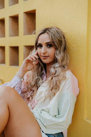 A Caucasian blonde pretty girl posing in the park under the sun with a summer outfit