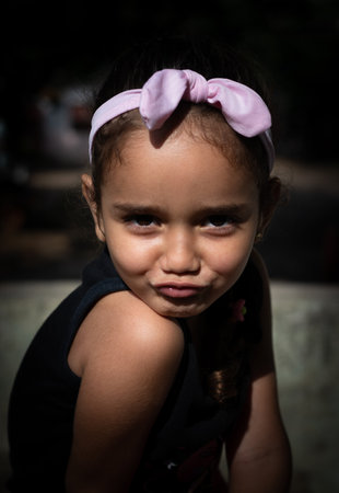 A vertical portrait of a cute little girl doing a duck face