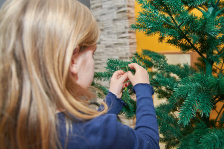A Serbian Caucasian girl decorating a Christmas tree indoorsの写真素材