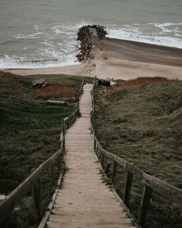 A beautiful shot of a wooden staircase leading to a touristic beach in Denmarkの写真素材