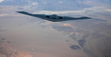 A stealth aircraft flying over the landscapes during daylight