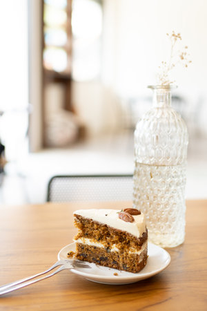 A vertical shot of a slice of nut cake near a decorative vase