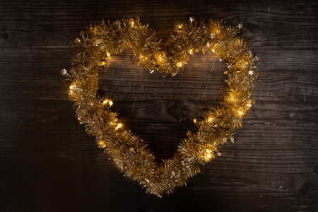 Heart-shaped garland with sparkling lights on a wood backgroundの写真素材