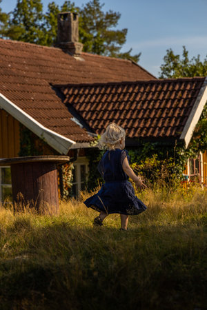 A small girl running on the grass near the rural houseの写真素材