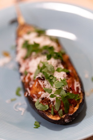 A baked eggplant with meat and cheese in a blue plateの写真素材