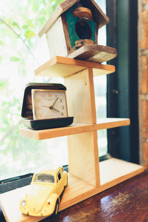 A vertical shot of a small wooden shelf with a clock and a toy carの写真素材