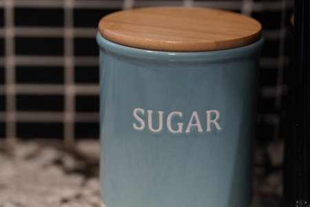 A closeup focus of a light blue ceramic sugar jar with a wooden lid