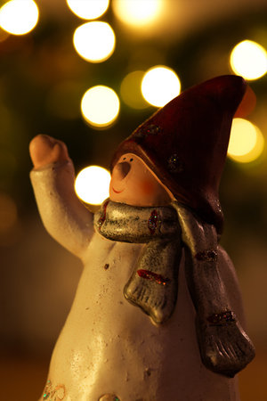 A vertical shot of a dwarf Christmas figure against bokeh lightsの写真素材