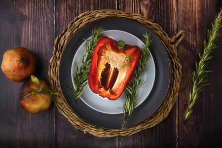 A top-view of half sliced red bell peper on a table with fresh greens on a rustic wooden tabの写真素材