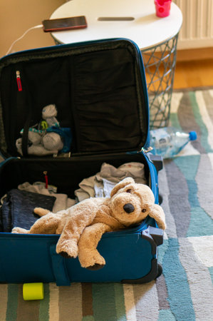 A vertical shot of an open suitcase with a plush dog toy