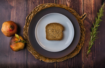 A top-view of a slice of bread on a white plate on a rustic wooden tableの写真素材