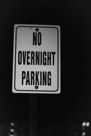 A grayscale shot of a street sign No Overnight Parking