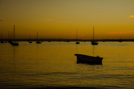 A beautiful shot of orange sunset over the boats in a calm clear seaの写真素材