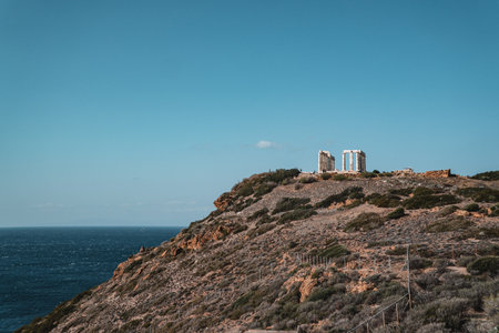 A beautiful shot of a hill and ruins of the Temple of Poseidon in Greecの写真素材