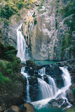 A mesmerizing waterfall view over the mossy rock formations in the forestの写真素材