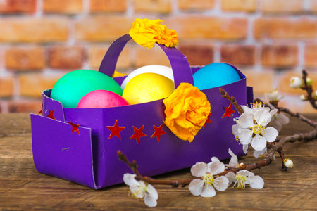 Beautiful composition with spring blossoms and a handmade paper basket full of dyed eggs